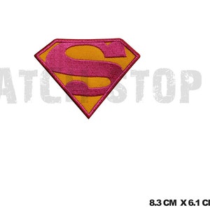 May include: Embroidered patch of the Superman logo. The patch features a yellow diamond shape with a pink "S" in the center. The patch measures 8.3 cm by 6.1 cm. The patch has a red border.