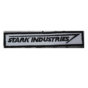 Puede incluir: Un parche rectangular con el texto "STARK INDUSTRIES" en negro, con borde blanco. El parche tiene un borde negro y un gráfico estilizado "7". Adecuado para ropa o accesorios.