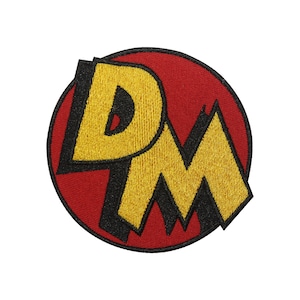 May include: Embroidered patch with the letters "PM" in yellow, outlined in black, on a red circular background. The design has a comic book aesthetic.