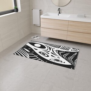 Könnte beinhalten: Eine rechteckige Badematte mit schwarz-weißem Muster und abstraktem Design. Das Design zeigt geschwungene Linien, Kreise und Punkte. Die Matte liegt auf einem gefliesten Boden in einem Badezimmer.