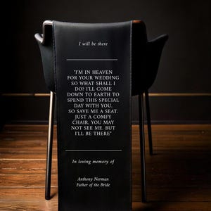 May include: A black fabric banner with white text that reads "I will be there" and a poem about being in heaven for a wedding. The banner is draped over the back of a black chair. The text at the bottom reads "In loving memory of Anthony Norman Father of the Bride."