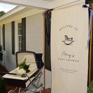 May include: A baby shower scene with a vintage stroller holding flowers and a banner that reads "Welcome to Mary's Baby Shower" with a rocking horse illustration. The banner also includes the date 09.21.2025.