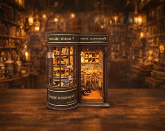 May include: A miniature wooden Magic Wand Shop model with detailed interior and exterior features. The shop has a curved front with the words "Magic Wand Shop" and "Magic Wand" in gold lettering. The interior is lit, showcasing shelves and items.