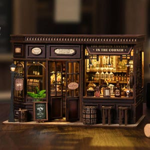 May include: A miniature wooden tavern model with intricate details. The model features a bar, shelves stocked with bottles, and a sign that reads "The Hidden Tavern in the Corner." The exterior includes a "Wine Shop" sign and a street lamp.