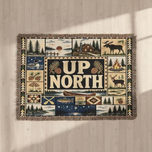 May include: A rectangular woven throw blanket featuring a central panel with the text UP NORTH. The design includes various nature-themed vignettes such as a moose, a deer, a campfire, a canoe, a loon, pine trees, and a cabin at sunset.