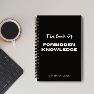 May include: A black spiral bound notebook with the text "The Book Of FORBIDDEN KNOWLEDGE open at your own risk" in white.