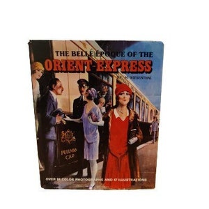 May include: A vintage book cover featuring a colorful illustration of people on a train. The title is "The Belle Epoque of the Orient Express" with the text "Over 54 Color Photographs and 47 Illustrations".