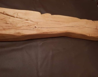 Può includere: Un lungo pezzo di legno invecchiato di colore marrone chiaro naturale. Il legno ha una consistenza ruvida e rustica e diverse crepe che corrono per tutta la sua lunghezza.