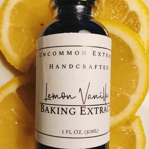 May include: A blue glass bottle with a white label that reads "Uncommon Extracts Handcrafted Lemon Vanilla Baking Extract 1 fl. oz. (30 ml)". The bottle is sitting on top of lemon slices.