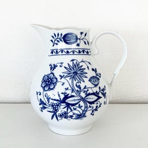 Könnte beinhalten: Ein Set aus drei Keramikbechern mit gesprenkelter, matter Oberfläche. Jeder Becher hat eine andere Farbe: hellblau, cremefarben und grau. Die Becher haben ein schlichtes, modernes Design und einen bequemen Griff.