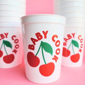 May include: White plastic cups with a red and green cherry design and the text "BABY COOK" printed on them.