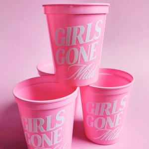 Pu&ograve; includere: Tre bicchieri di plastica rosa con lettere bianche che recitano "Girls Gone Wild" in un font retr&ograve;. I bicchieri sono impilati uno sopra l'altro.