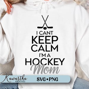 May include: White hoodie with black text that reads "I can't keep calm I'm a hockey mom" with a hockey stick and puck graphic above the text. The word "mom" is in gray text.