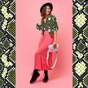 K&ouml;nnte beinhalten: Eine Frau tr&auml;gt eine gr&uuml;n-schwarz gemusterte Bluse, eine rosa Hose und schwarze Schuhe und h&auml;lt eine wei&szlig;e Handtasche. Der Hintergrund ist rosa, mit einem Schlangenhautmuster an den Seiten.