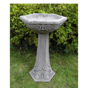 May include: A grey concrete bird bath with an octagonal basin and a decorative base. The bird bath is on a grassy lawn.