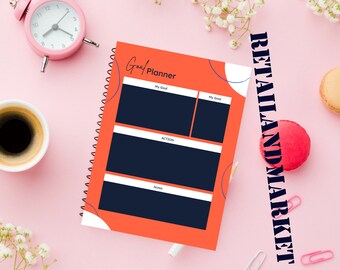 May include: An orange goal planner with a spiral binding. The planner has sections for "My Goal", "Action", and "Notes".