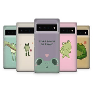 Pode incluir: Conjunto de seis capas para telefone com diferentes ilustrações de sapos. As capas são todas pretas com uma janela de plástico transparente na parte de trás. Os sapos são todos verdes e têm expressões diferentes. O texto em uma capa diz "Não toque no meu telefone".
