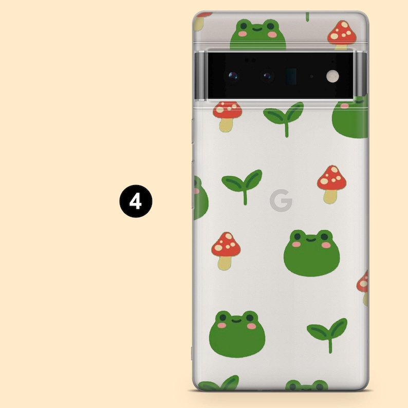 May include: A white phone case with a green frog and red mushroom pattern. The case has a clear back and a black camera lens.