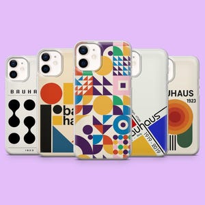 Puede incluir: Cinco fundas para iPhone con diseños inspirados en la Bauhaus en varios colores. Las fundas presentan formas geométricas y el texto "BAUHAUS 1923" y "Bauhaus 1919-2019". Se muestran sobre un fondo lila claro.