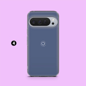 May include: A clear phone case with a blue-gray backing. The case has a camera cutout at the top and a white sun-like graphic in the center. The phone case is designed to fit a specific phone model.