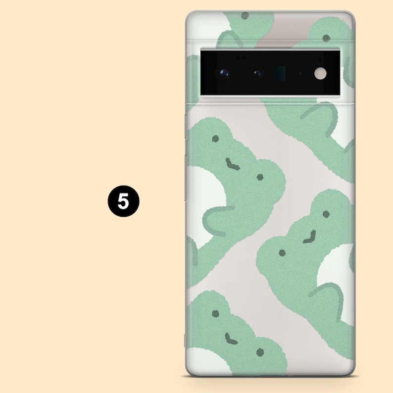 May include: A clear phone case with a white background and a pattern of green frogs. The case has a black camera lens cutout.