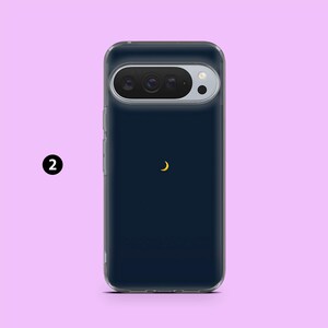 May include: A navy blue phone case with a clear border. The case features a gold crescent moon design. The phone's camera is visible at the top. The number "2" is in a black circle on the left side.
