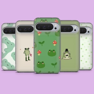 May include: Five phone cases with various frog-themed designs. The cases feature patterns of frogs, mushrooms, and leaves in shades of green and white. One case has a frog wearing a top hat and bow tie.