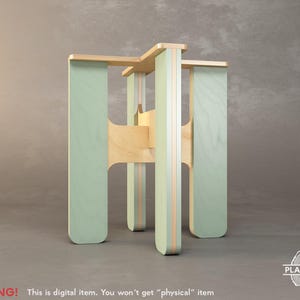 May include: A light green wooden stool with a unique, geometric design. The stool is made of plywood and has a natural wood finish.