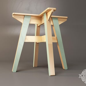 May include: A wooden table with a light green painted finish. The table has a square top and four legs that are angled outwards. The table is made of plywood and has a simple, modern design.