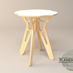 Könnte beinhalten: Ein runder weißer Tisch mit einem einzigartigen, geometrischen Holzfuß. Der Tisch ist aus Sperrholz gefertigt und hat eine natürliche Holzoptik.