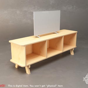 May include: A light-colored wooden TV stand with three open compartments and angled legs. A flat-screen TV is placed on top. The stand has a mid-century modern design. The text "WARNING! This is digital item. You won't get "physical" item" is at the bottom.