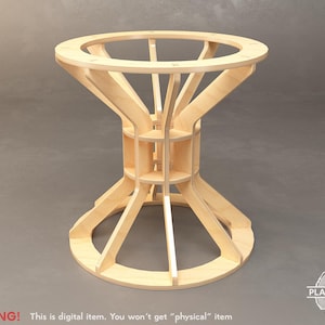 May include: A light-coloured, unfinished wooden table with an unusual hourglass design. It has a circular top and base, connected by angled supports and a central structure with small shelves. The text "PLANDICRAFT" is visible.