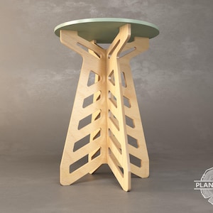 Puede incluir: Una mesa auxiliar moderna de madera, con una tapa redonda verde salvia. La base está construida con madera clara con un diseño geométrico abierto. La mesa mide aproximadamente 61 cm de altura.
