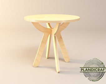 May include: A light wood side table with a round top and three legs. The legs are shaped like an X and are connected to the top of the table.