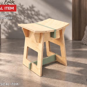 Peut inclure: Un tabouret en bois clair doté d'une assise incurvée et d'accents vert sauge. Le tabouret présente une structure géométrique avec des côtés ouverts et une barre de support horizontale. Le texte indique : DIGITAL ITEM, FREE CUSTOM SIZE & THICKNESS, NO PHYSICAL ITEM.