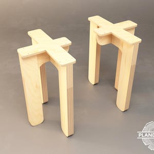 May include: Two unfinished wooden stools with a cross-shaped top and four legs. The stools are made of plywood and have a natural wood finish.