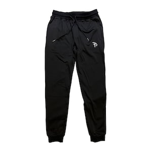 May include: Black sweatpants with a white "PB" logo on the right leg. The sweatpants have a drawstring waistband and a cuffed bottom.