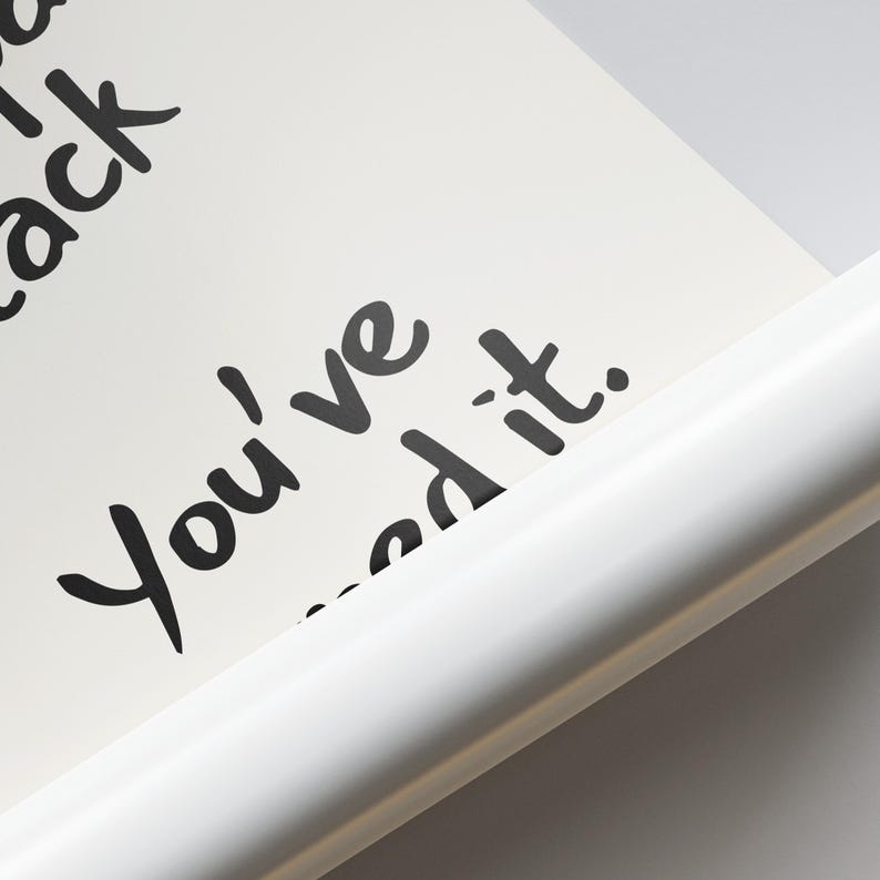May include: A close-up of a white poster with black handwritten text that reads "You've...ed it." The poster is partially rolled, revealing a white edge. The background is a light gray.