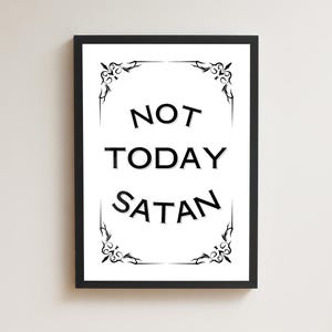 Peut inclure: Une affiche encadrée avec le texte NOT TODAY SATAN en lettres capitales noires et grasses. Le motif est centré sur un fond blanc et entouré d'une bordure décorative en filigrane noir, le tout dans un cadre noir simple et épuré.