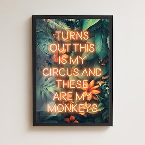 May include: A framed art print with a black border. The artwork features a vibrant jungle scene with lush green leaves and orange flowers. The neon-style text reads, "TURNS OUT THIS IS MY CIRCUS AND THESE ARE MY MONKEYS."