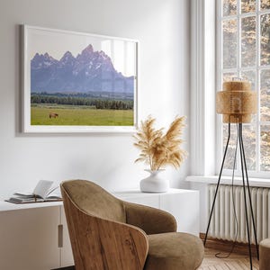 A stunning snow-covered mountain framed or unframed print from Grand Teton National Park with a beautiful horse grazing the grass in the forefront.