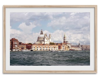 May include: A framed landscape photograph of the Venice skyline featuring the Santa Maria della Salute basilica with its large dome, surrounding historic buildings, and a body of water in the foreground under a cloudy blue sky.