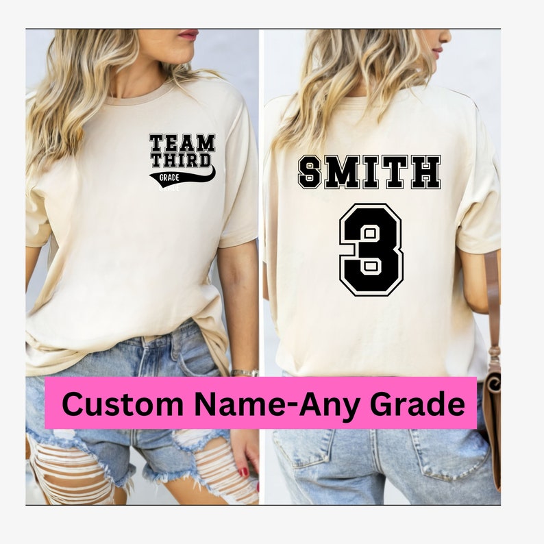 K&ouml;nnte beinhalten: Ein beiges T-Shirt mit schwarzem Text, der auf der Vorderseite "Team Third Grade" und auf der R&uuml;ckseite "Smith 3" lautet. Das Shirt wird von einer Person in Jeans-Shorts getragen.