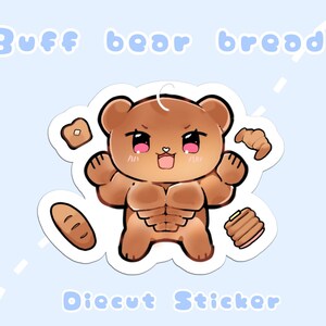 May include: A die-cut sticker featuring a muscular brown bear with bread-themed elements. The bear has a stern expression and is surrounded by illustrations of bread, including a croissant, loaf, and toast. The text "Buff bear bread" is at the top.