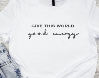May include: White t-shirt with the text "GIVE THIS WORLD good energy" printed in black.