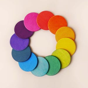 Könnte beinhalten: Ein Farbkreis aus Holzscheiben in verschiedenen Farbtönen von Rot, Orange, Gelb, Grün, Blau, Indigo und Violett.