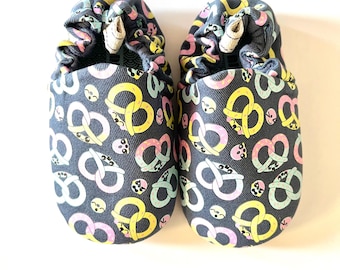 Zapatos de bebé con suela blanda y estampado de pretzel de Poco Nido. Talla 20 (Eur.) y 4 (UK). Apto para pies descalzos.