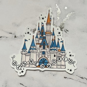 May include: A white sticker featuring a detailed illustration of a castle with blue and orange turrets, flags, and the text "DISNEY WORLD" in a banner. Black stars surround the castle.
