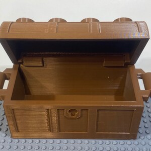 May include: A brown wooden treasure chest with a hinged lid and two handles. The chest is open and empty.