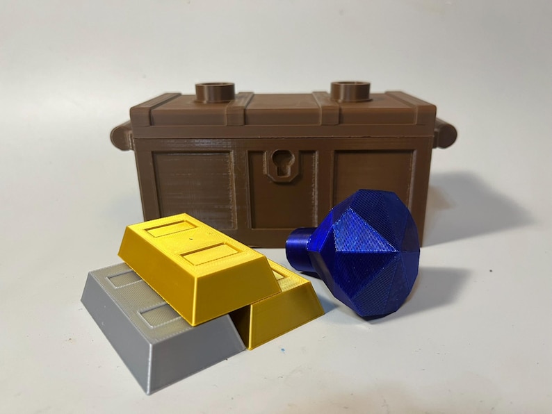 May include: A brown wooden treasure chest with a keyhole, two gold bars, and a blue gemstone.